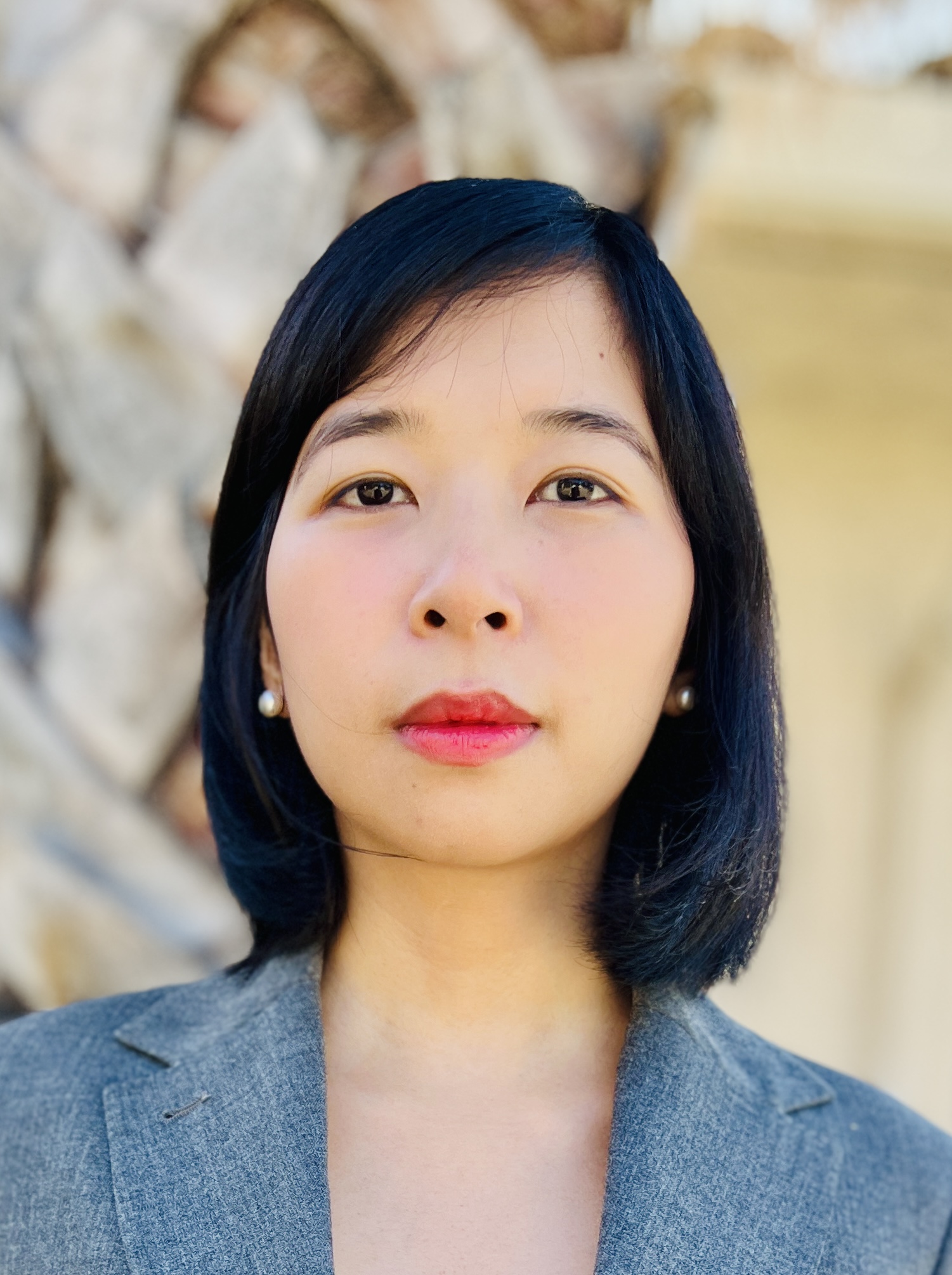 A photo of Lan Le wearing a grey blazer and pearl earrings